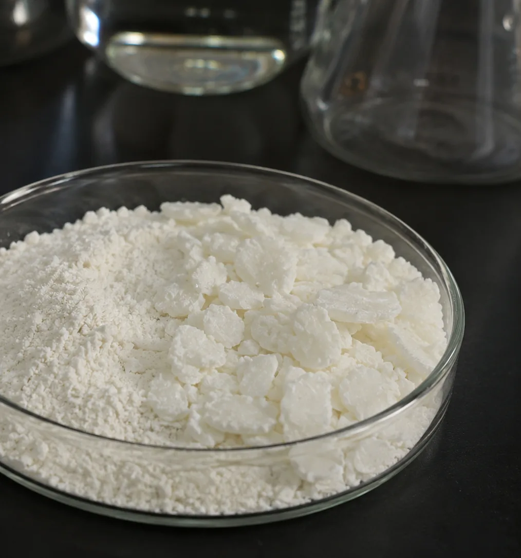 Off-white aleuritic acid powder and flakes in a laboratory dish