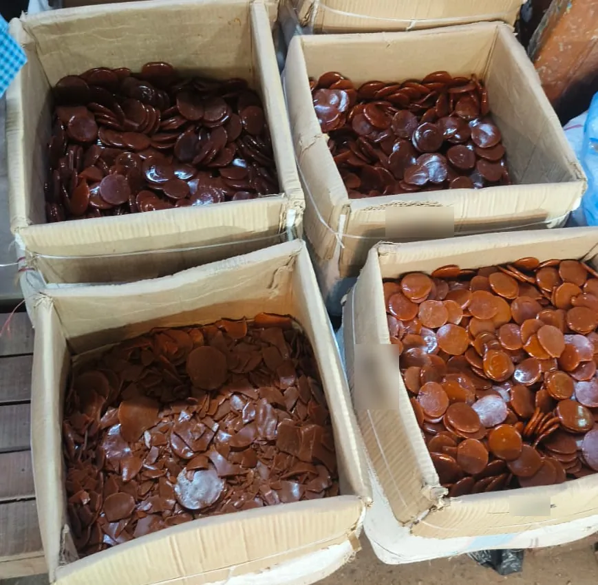 Handmade button lac discs in cartons, from orange to deep red-brown