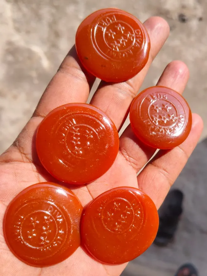 Stamped orange button lac discs held in hand