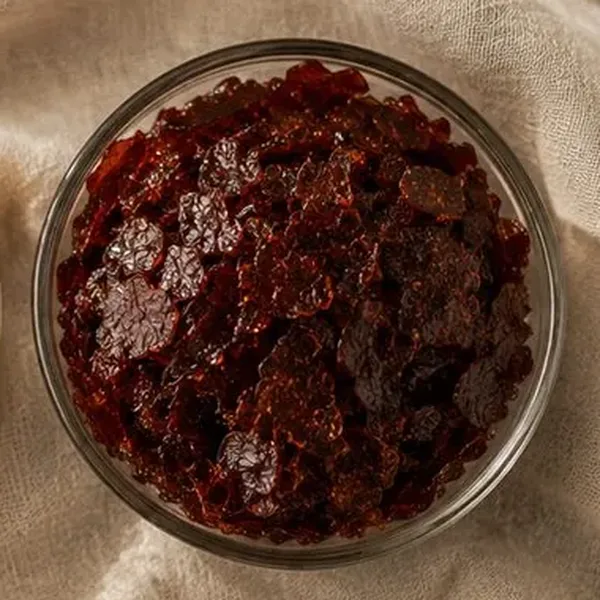 Garnet shellac flakes in a glass bowl, dark red-brown grade